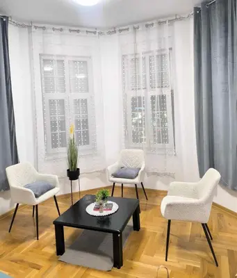 a living room with a table and chairs and windows at Urban Aura Belgrade in Belgrade