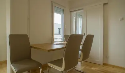 a dining room with a table and chairs and a window at Premium stan Novi Beograd in Novi Beograd