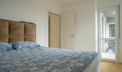 a bedroom with a bed and a large window at Premium stan Novi Beograd in Novi Beograd