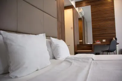 a bedroom with a bed with white pillows and a desk at Olivia Rooms in Belgrade