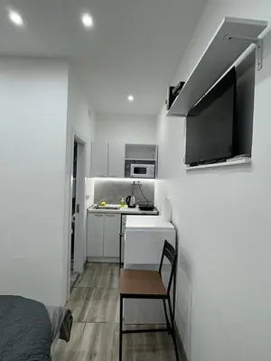 a small white kitchen with a sink and a table at Global City Studio in Belgrade