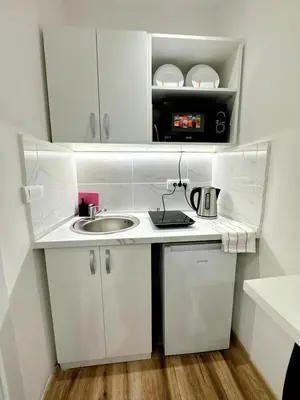 a small white kitchen with a sink and a microwave at Global City Studio in Belgrade