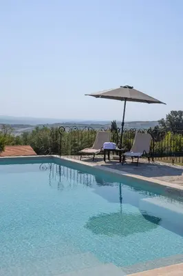 a swimming pool with an umbrella and two chairs and a table at Ozoni & Spa in Sopot