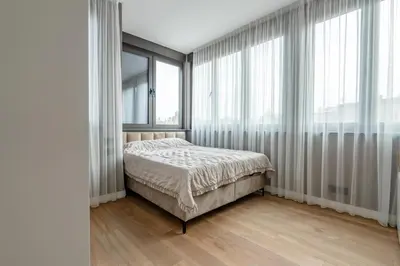 a bedroom with a bed and large windows at Kondina Suites in Belgrade