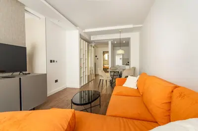 a living room with an orange couch and a table at Kondina Suites in Belgrade