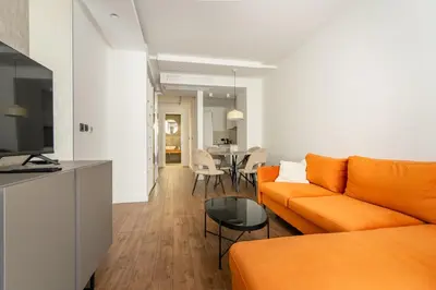a living room with an orange couch and a table at Kondina Suites in Belgrade
