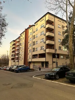 a parking lot with cars parked in front of a building at Oaza Mirijevo in Mirijevo