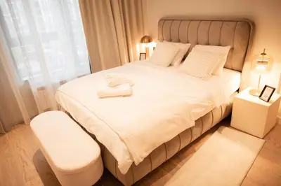 a bedroom with a large white bed with a white stool at Belgrade Simfonia - One bedroom apartment in Belgrade