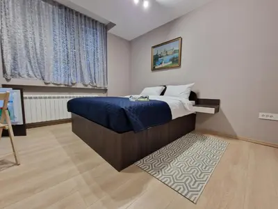 a bedroom with a bed with blue sheets and a rug at Center Prestige Apartments in Belgrade