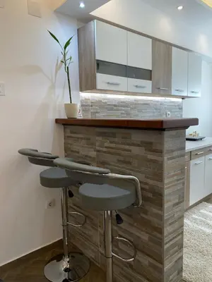 a kitchen with a counter and a bar with stools at Surčin Centar apartment in Surčin