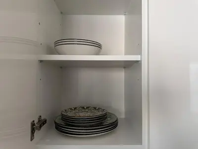 a white cupboard with plates and bowls on top at Beldorado Apartments - Belgrade Waterfront Luxury Apartment Amber in Belgrade