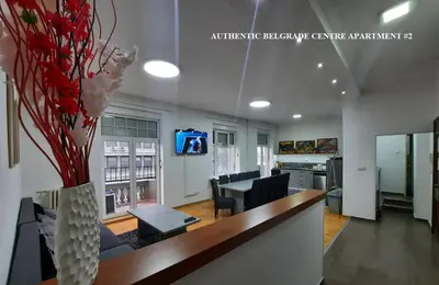 a living room with a table and chairs and a vase with flowers at Authentic Belgrade Centre Apartments for large groups, Republic Square - Up to 47 People in 5 Apartments in Belgrade