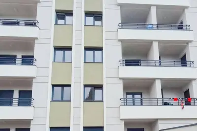 a white apartment building with people on the balcony at Urban Haven in Ledine