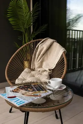 a wicker chair with a coffee table and a book at SD Luxury Apartment - Belgrade Waterfront - KARE Design - River View in Belgrade