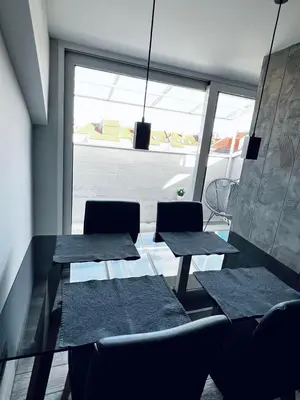 two tables and chairs in a room with a window at New Grey in Novi Beograd