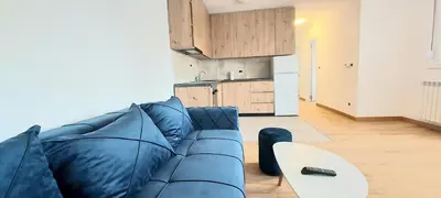 a living room with a blue couch and a table at Magenta Zvezdara in Belgrade