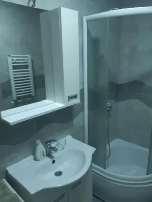 a white bathroom with a sink and a shower at Stil Apartman in Smederevo