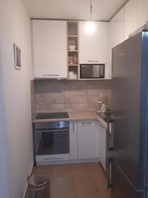 a kitchen with white cabinets and a stainless steel refrigerator at Stil Apartman in Smederevo