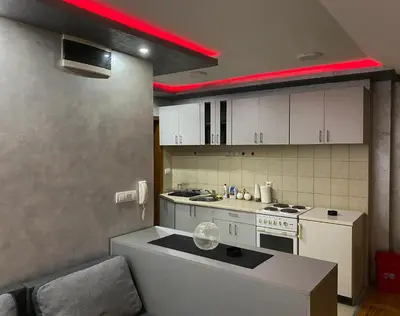 a kitchen with white cabinets and a red light at GM Apartman Obrenovac in Obrenovac