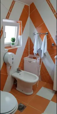 an orange and white bathroom with a toilet and a sink at Lux Apartments With Pool Dex in Zemun Polje