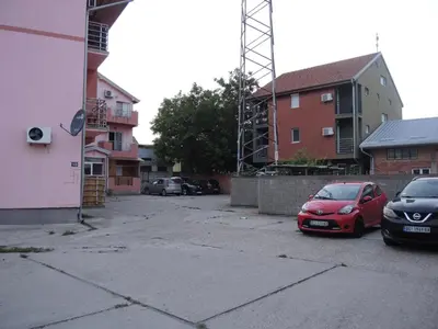 two cars parked in a parking lot next to buildings at Apartments 43 in Krnjača