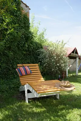 a wooden bench with pillows and a table in the grass at Kuća za odmor u Banatu in Debeljača