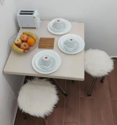 a table with white seats and a bowl of fruit at Apartment Washington in Belgrade