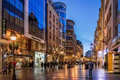a city street at night with people walking around at Apartment Washington in Belgrade