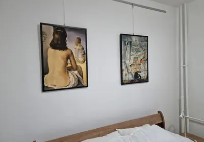 three paintings on a wall above a bed at Dali Arena Business Comfort Apartment 2 Bedrooms King Size in Belgrade