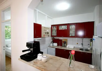 a kitchen with red cabinets and a coffee maker on a counter at Dali Arena Business Comfort Apartment 2 Bedrooms King Size in Belgrade