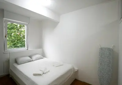 a white bedroom with a bed with two towels on it at Dali Arena Business Comfort Apartment 2 Bedrooms King Size in Belgrade