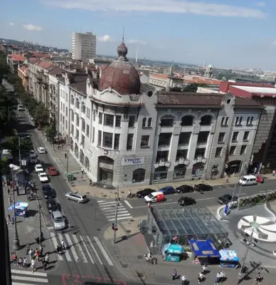 a large white building with a red roof on a city street at Apartment Baroque in Belgrade