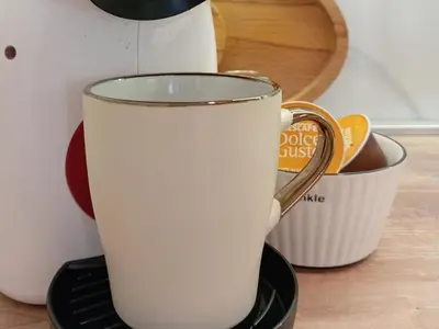 a cup of milk sitting on a stand next to a mug at Tera apartment Zemun in Belgrade