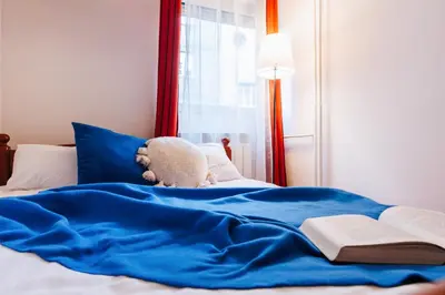 a teddy bear laying on a bed with a blue blanket at Big Company 3min to Republic Square Renovated in Belgrade