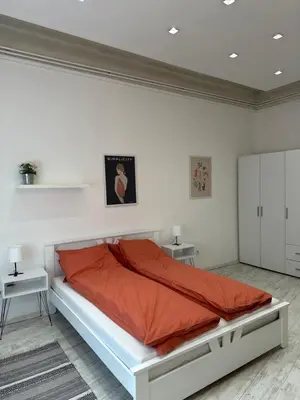 a white bedroom with a large bed with orange sheets at Sofi1 in Belgrade