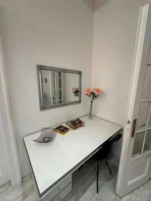 a white desk with a mirror and a vase of flowers at Sofi1 in Belgrade