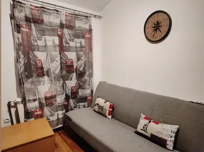 a couch in a living room with a clock on the wall at Stan na dan BALANS in Ledine