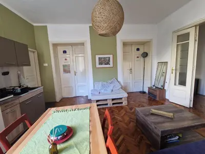 a living room with a table and a kitchen at Central Station Private Rooms in Belgrade