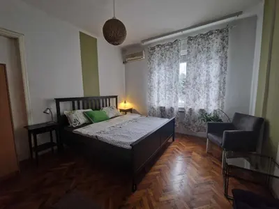 a bedroom with a bed and a chair and a window at Central Station Private Rooms in Belgrade