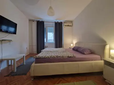 a bedroom with a bed and a desk and a television at Central Station Private Rooms in Belgrade