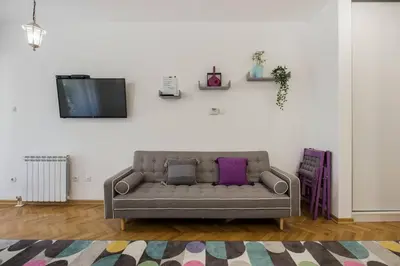 a living room with a couch and a tv on a wall at Studio apartment Duda in Karaburma