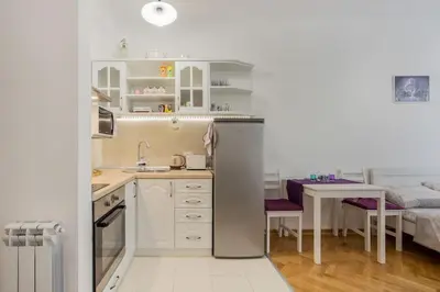 a kitchen with a refrigerator and a table and a bed at Studio apartment Duda in Karaburma
