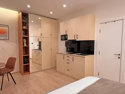 a kitchen with white cabinets and a table and a chair at Terazije Center Apartments in Belgrade