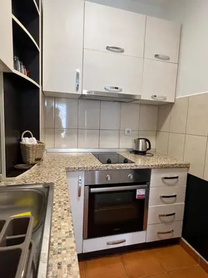 a kitchen with white cabinets and a sink at App Titan in Stara Pazova