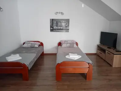 two beds in a room with a tv and a table at Apartman M Batajnica in Batajnica