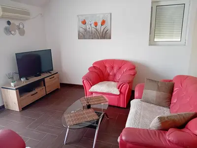 a living room with two red chairs and a tv at Apartman M Batajnica in Batajnica