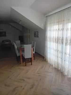 a dining room with a table and chairs and curtains at Apartman M Batajnica in Batajnica