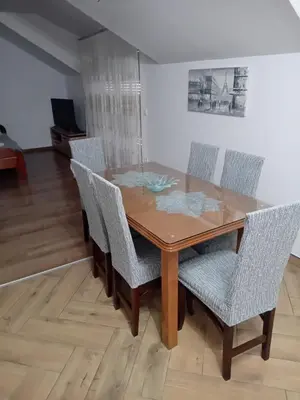 a dining room table with chairs and a wooden floor at Apartman M Batajnica in Batajnica