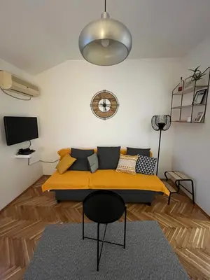 a living room with a couch and a clock on the wall at Apartman Stevan in Pančevo
