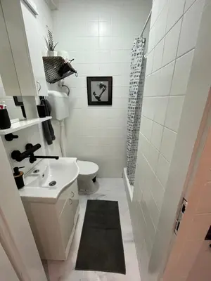 a white bathroom with a sink and a toilet at Apartman Stevan in Pančevo